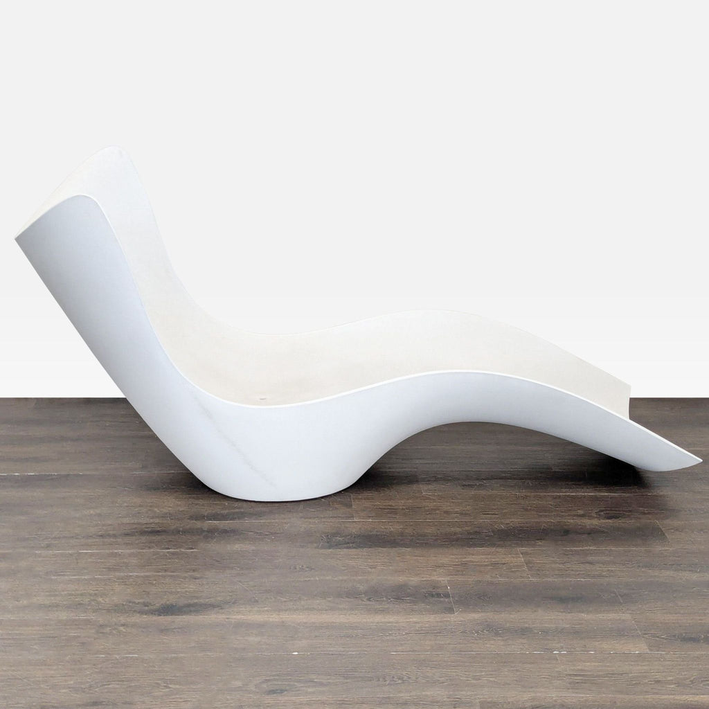 Side view of a single white Vondom lounge chair with wave-like ergonomic curves on wood floor.