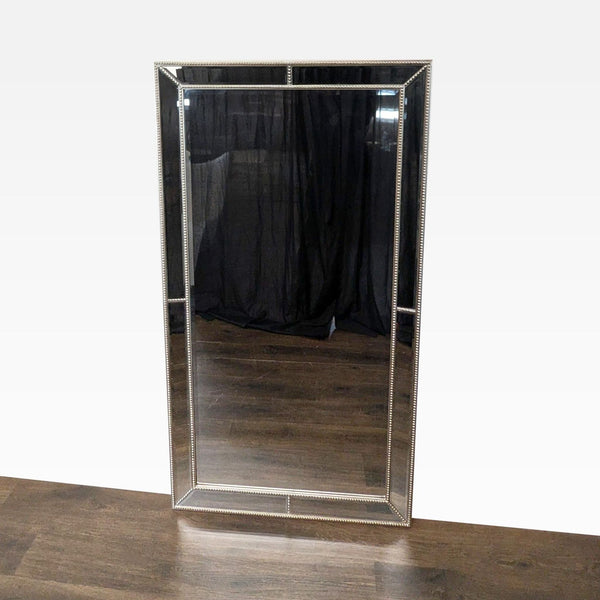 1. Rectangular mirror with beaded frame standing on a wooden floor, reflecting dark curtains in the background.