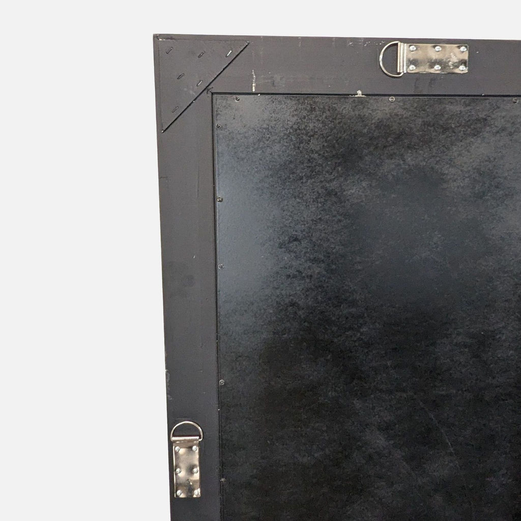 2. Close-up of the back corner of a rectangular mirror, showing black panel and metal hanging hardware.