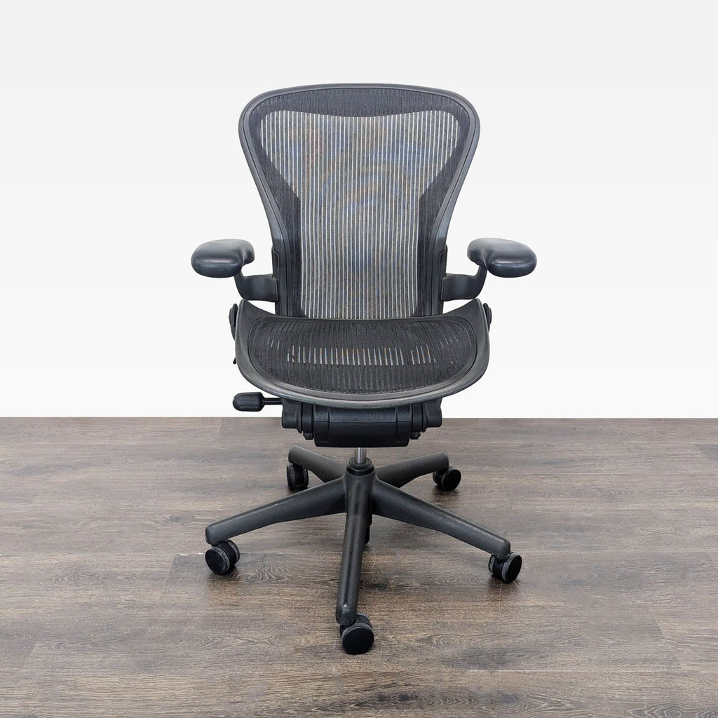 Herman Miller Aeron ergonomic office chair with mesh seat, adjustable arms, and rolling casters.