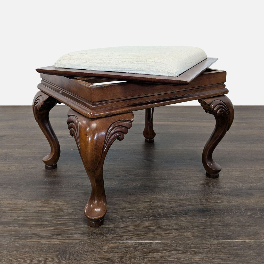 Convertible ottoman offering both seating and side table use with a neutral cushion and ornate cabriole legs.