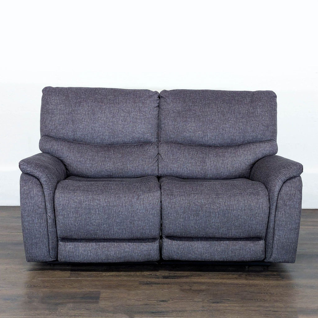 Gray Living Spaces loveseat with padded cushions, armrests, and electric recline feature for two people.