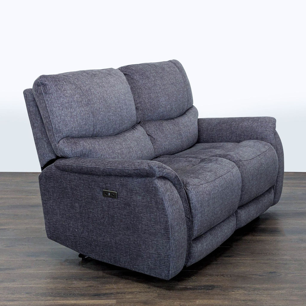 Living Spaces loveseat in durable gray fabric, seats two, with cozy cushions, armrests, and electric recliner.