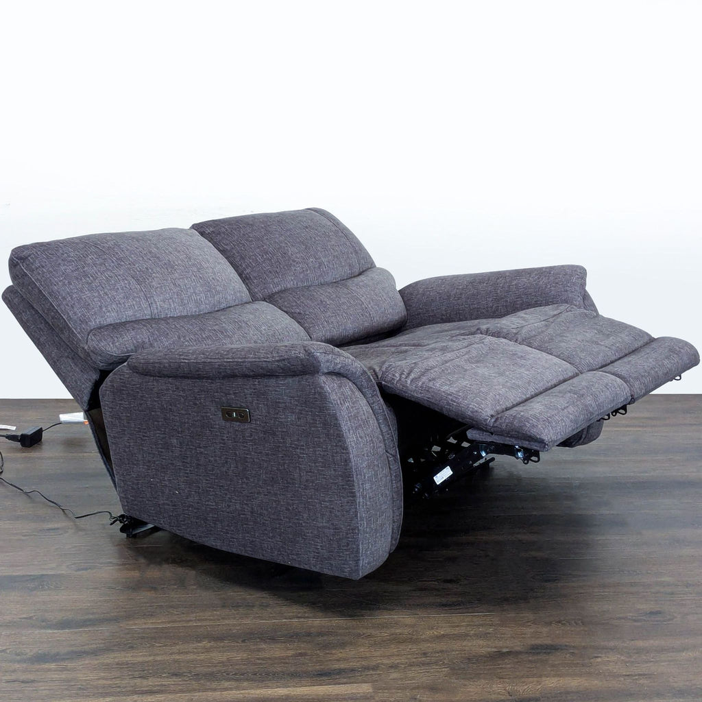 Modern gray loveseat by Living Spaces, featuring soft upholstery and push-button reclining for added comfort.