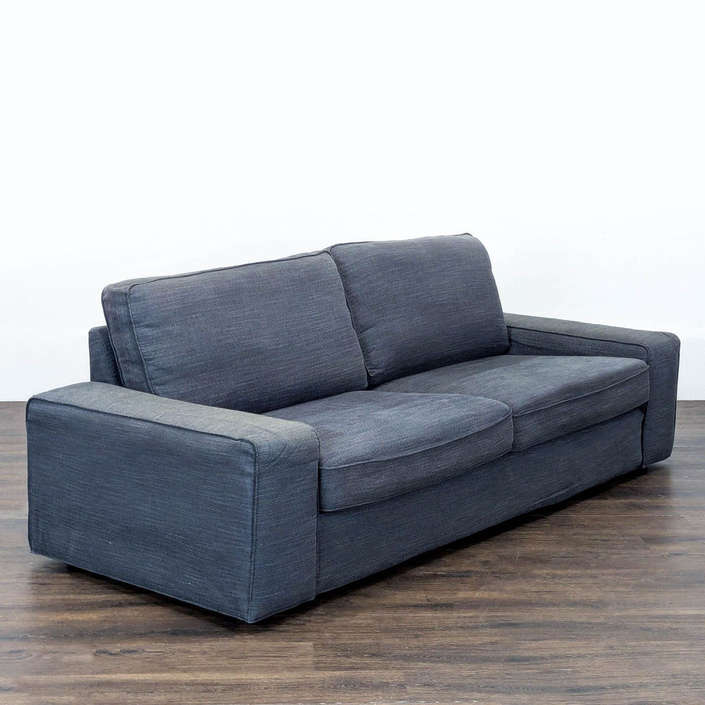 Modern dark gray Ikea sofa seats three, featuring durable build, comfortable cushions, and simple design.