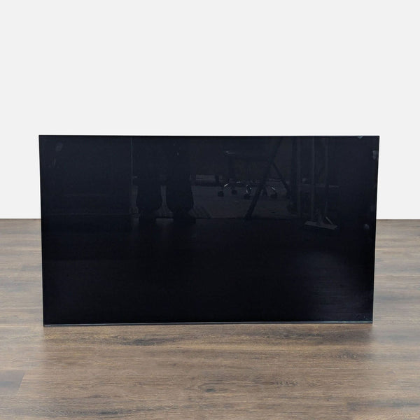 1. Front view of a Sony TV with a sleek, black, reflective screen on a wooden floor.