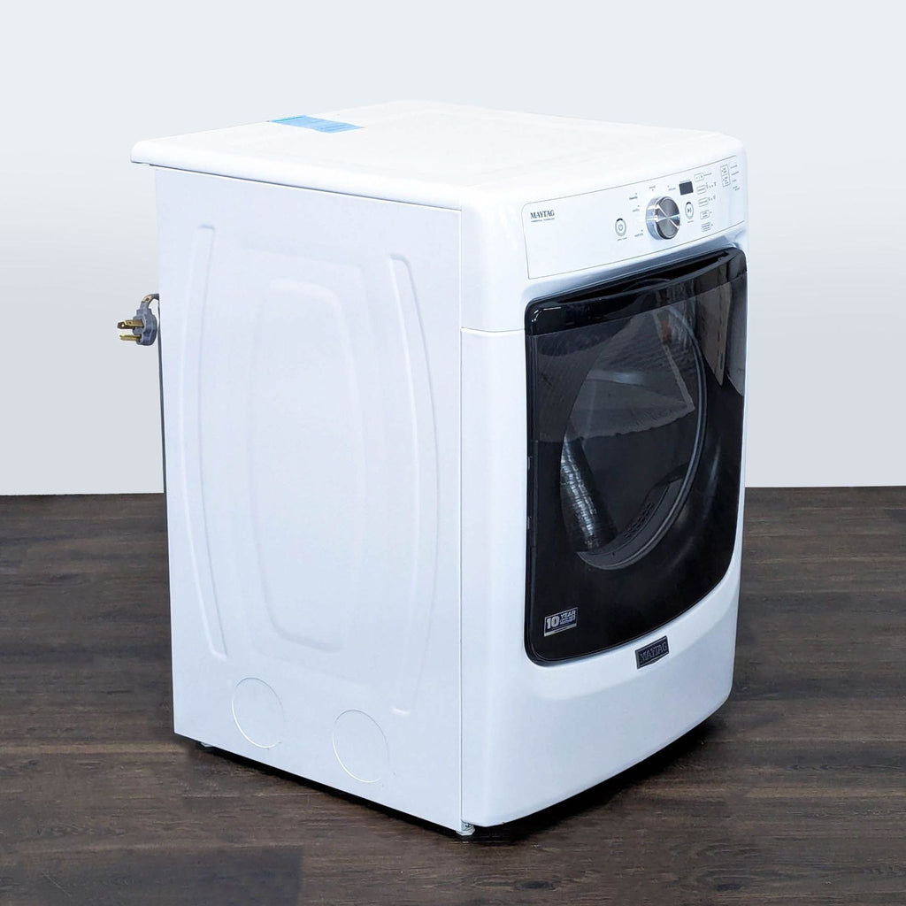 Angled side view of the sleek, white Maytag front load dryer, featuring a modern black-trimmed door.
