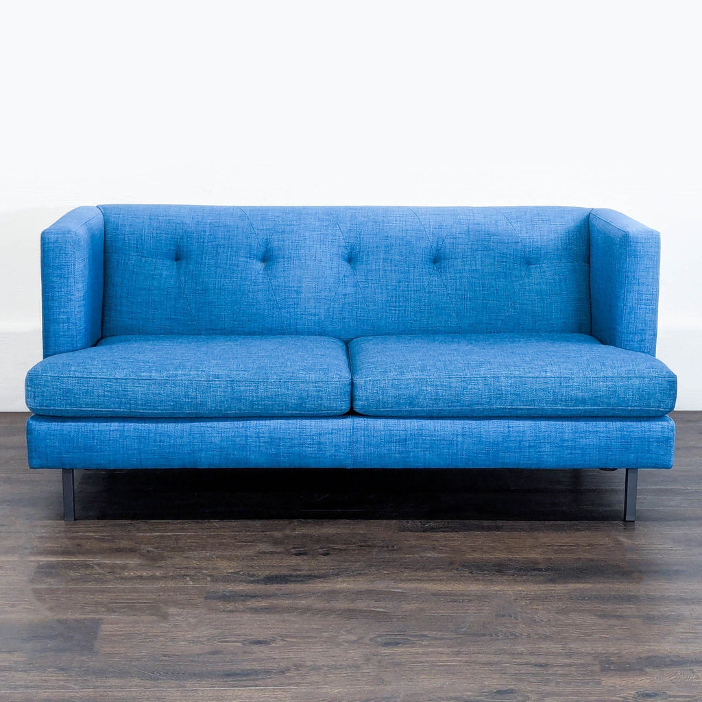 1. Modern blue CB2 loveseat with tufted back cushions and slim metal legs, ideal for small spaces.