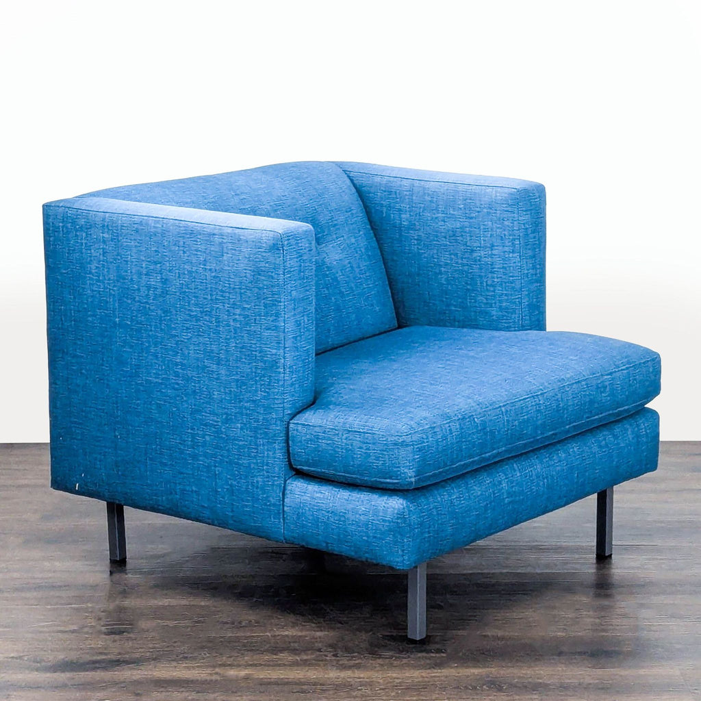 2. Angled side view of a modern blue CB2 lounge chair featuring plush seating and metal legs for support.  