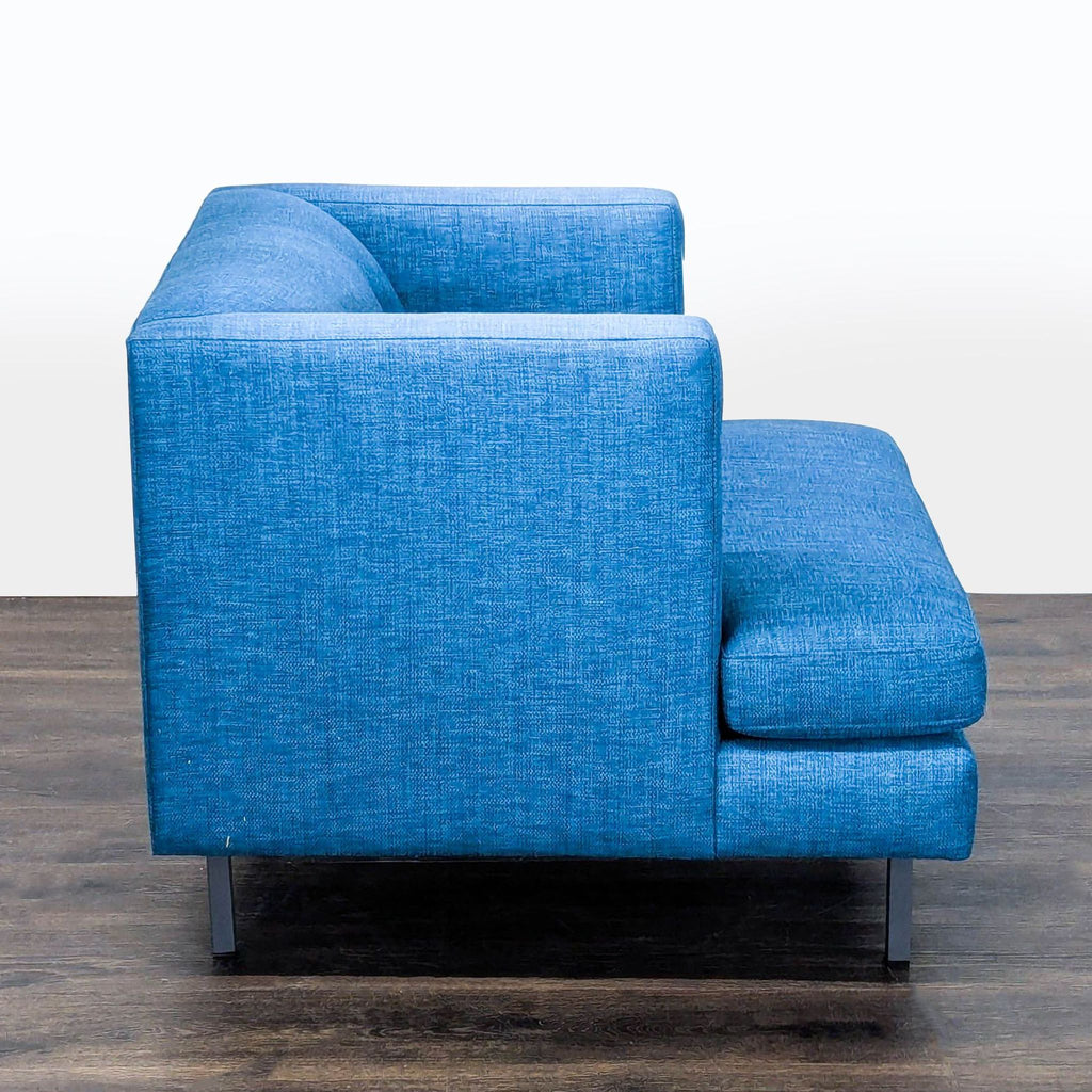 3. Side profile of a blue CB2 lounge chair, showcasing its modern armrests, deep seat, and sturdy metal legs.