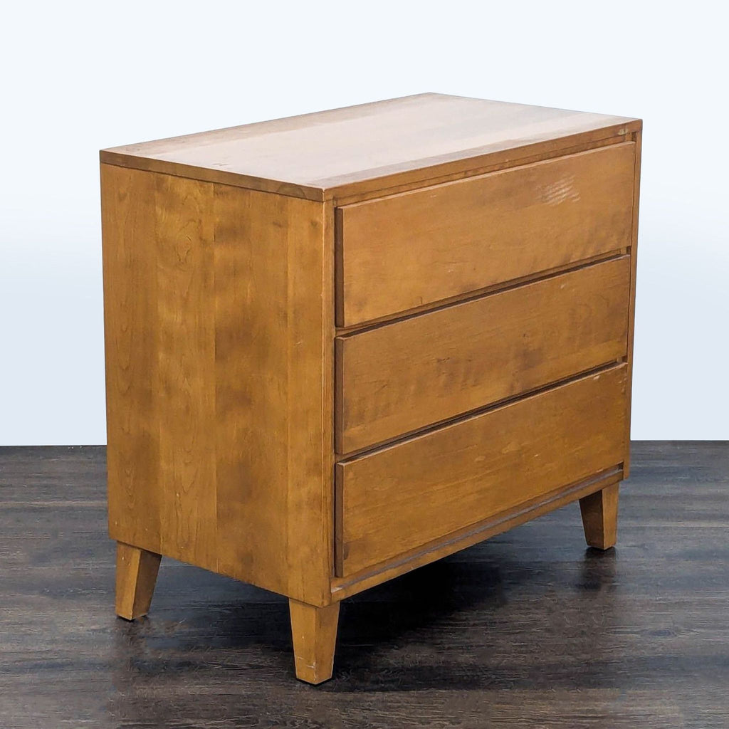 Mid-century modern Conant Ball dresser, solid wood, natural finish, viewed from an angle with closed drawers.