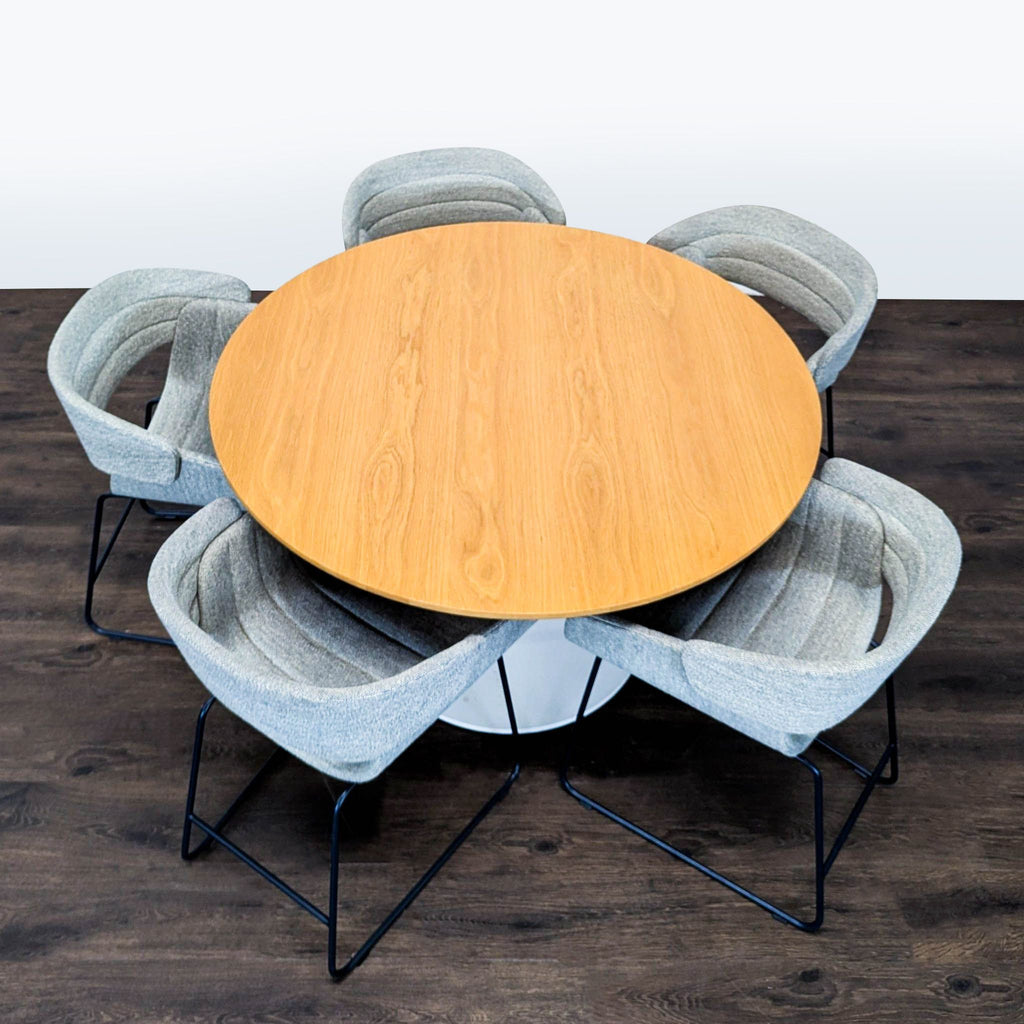 Modern dining ensemble from Blu Dot: round wood table with white base and five chic, cushioned chairs.