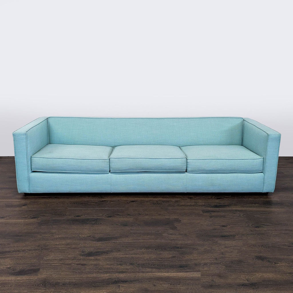 1. CB2 3-seat sofa in light blue fabric, modern design with clean lines, shown from the front on dark wood floor.  