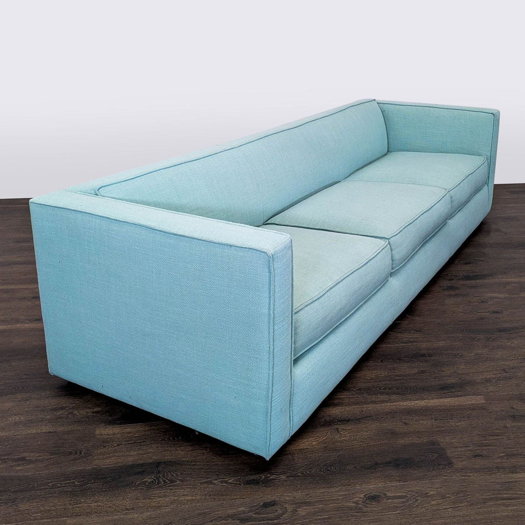 2. Angled view of a CB2 light blue 3-seat sofa, highlighting its boxy arms, spacious seating, and sleek style.  