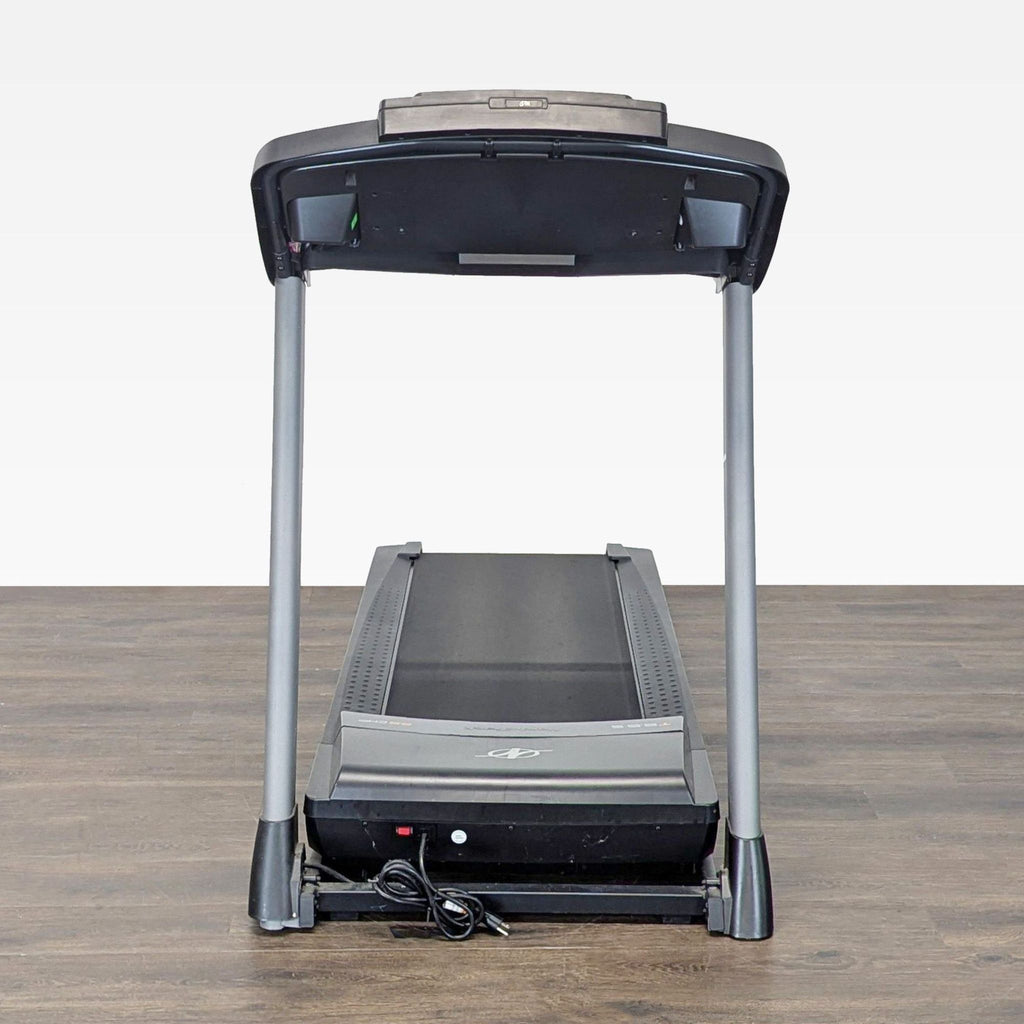 3. Rear view of a NordicTrack treadmill on a wooden floor, showing its robust construction and power cord.