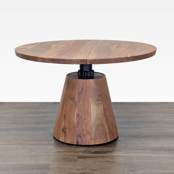 Round industrial pedestal dining table by Crate and Barrel, adjustable acacia wood top on threaded metal support.
