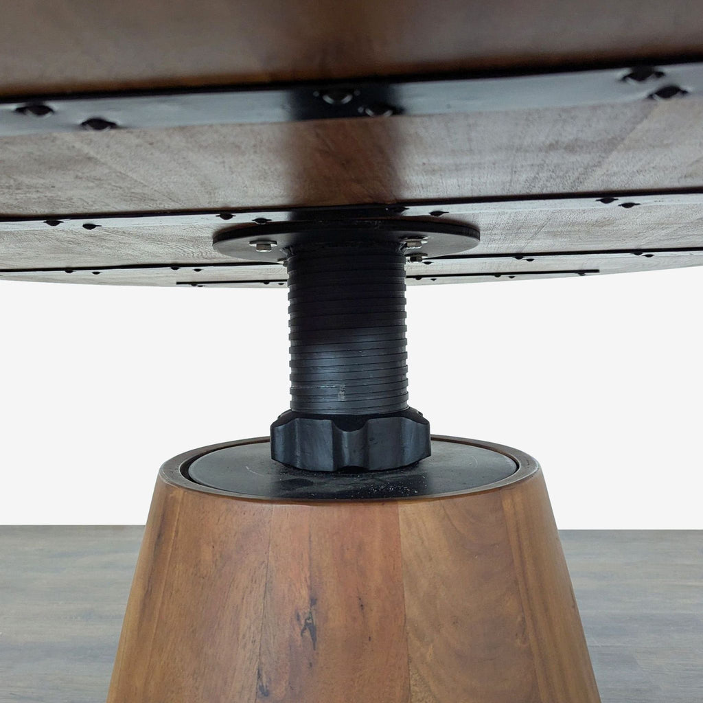 Crate and Barrel round acacia dining table, features adjustable height and a sturdy metal-accented base.