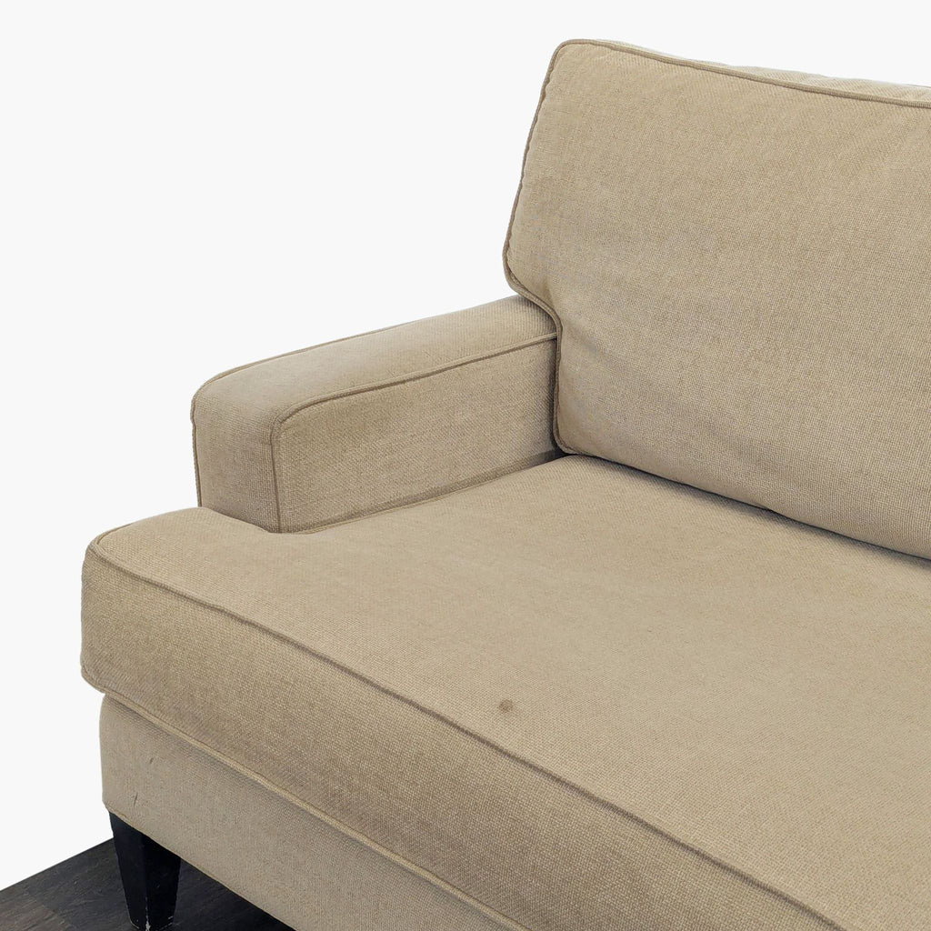 Close-up of the armrest and cushion of a beige Pier 1 Imports 3-seat sofa, highlighting its fabric texture.
