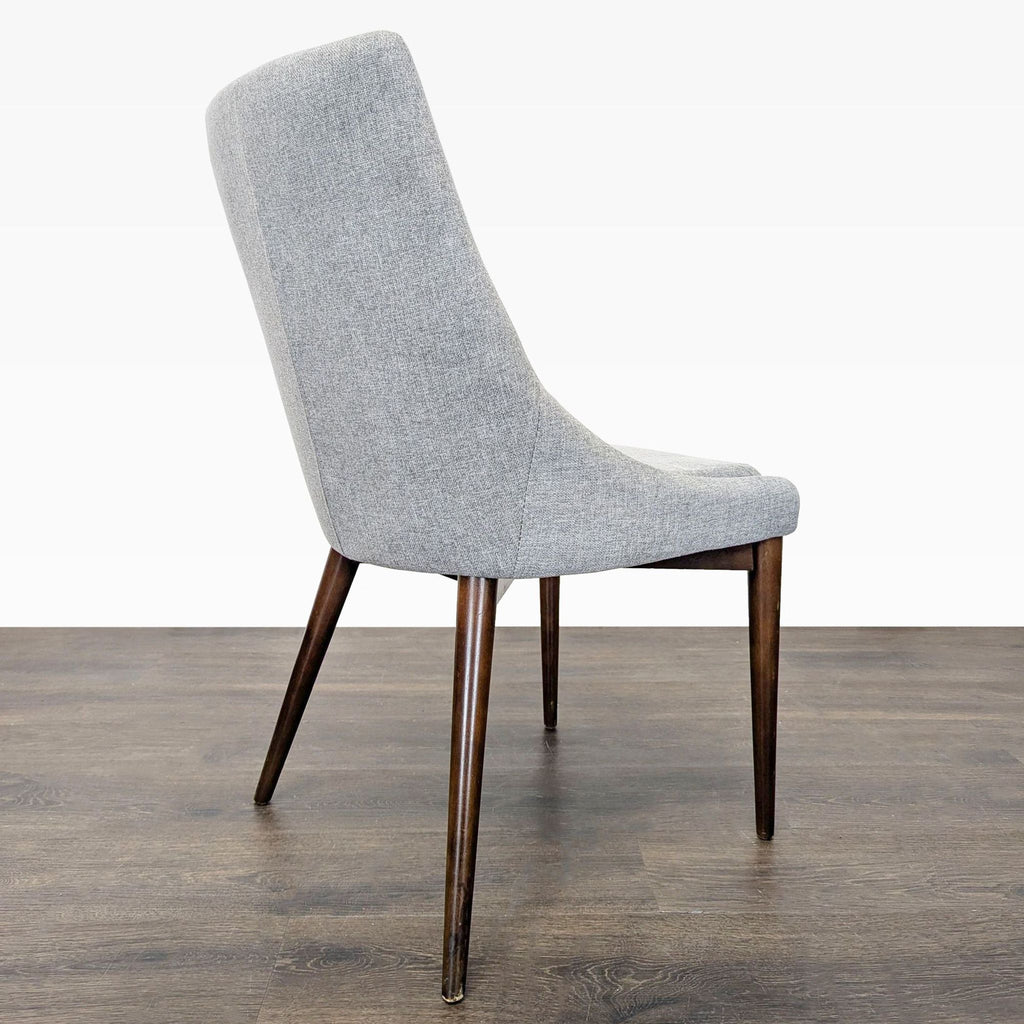 Elegant dining chair in mid-century design, upholstered seat and angled wooden legs for stylish comfort.