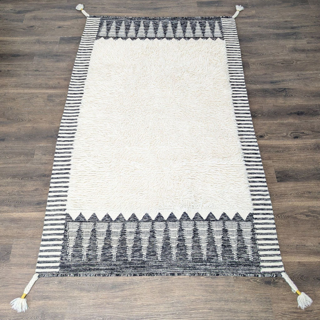 West Elm rug with black and white geometric border, soft shag center, modern patterns, and elegant style.