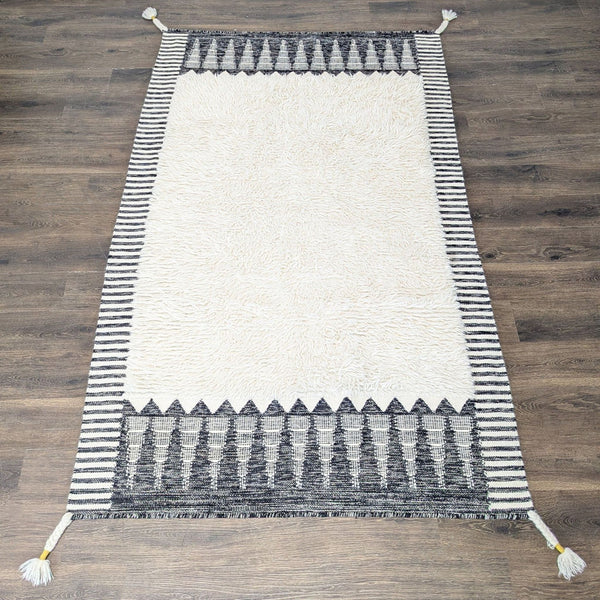 West Elm rug with black and white geometric border, soft shag center, modern patterns, and elegant style.