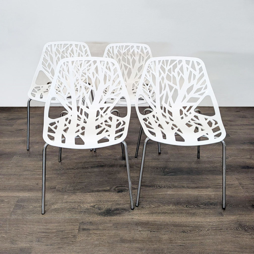 Set of four modern white chairs with tree branch cutout design and metal legs, ideal for dining or office use.