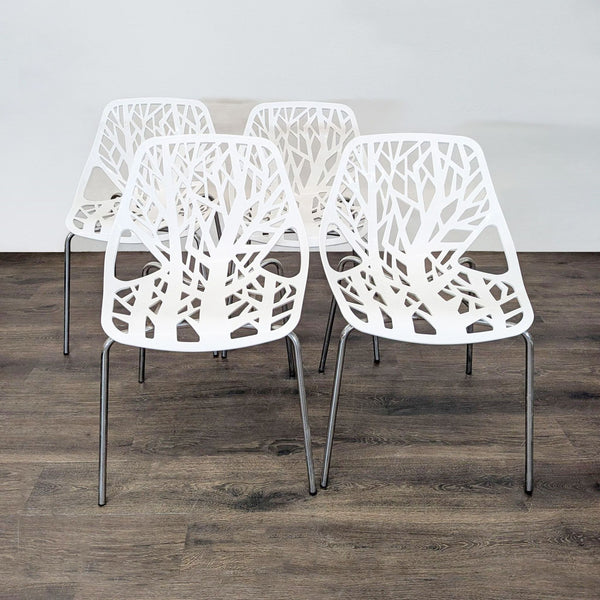 Set of four modern white chairs with tree branch cutout design and metal legs, ideal for dining or office use.