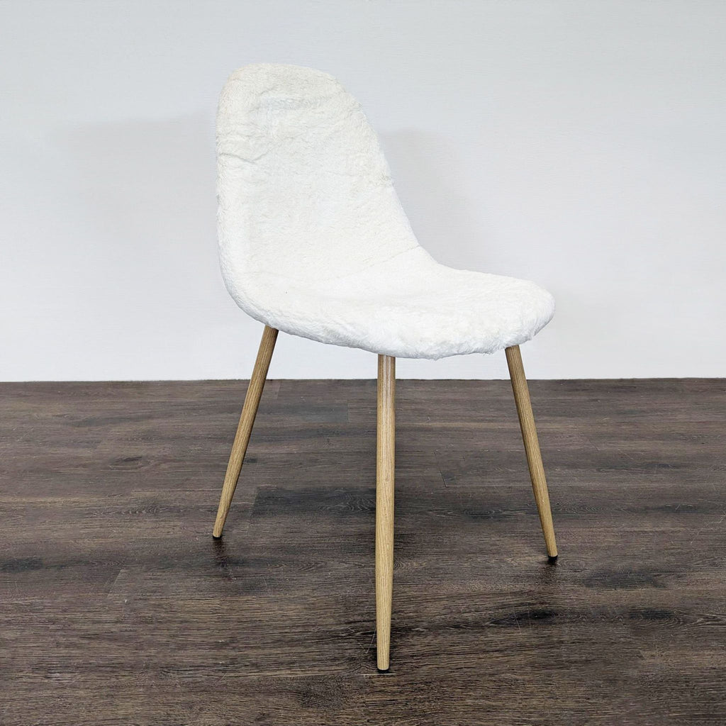 Modern dining chair with white fake fur cover and wood legs, angled on a dark floor, for dining room use.