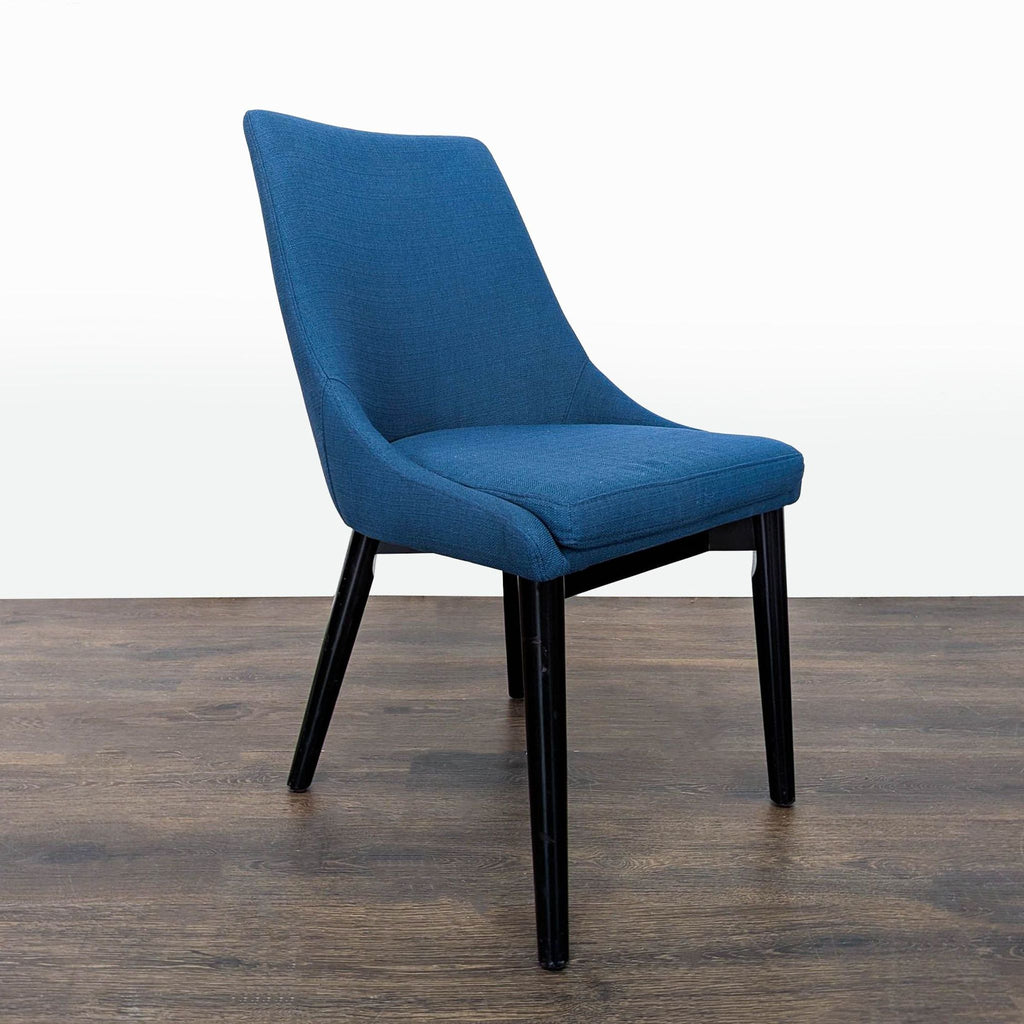 2. Side angle of a Modway dining chair featuring blue fabric, curved backrest, and black tapered legs.