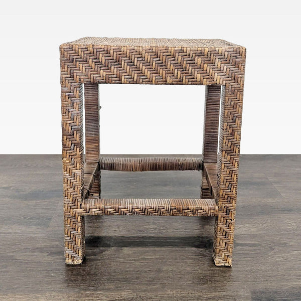 1. Square woven rattan stool with a chevron pattern, displayed on a dark wood floor against a white background.