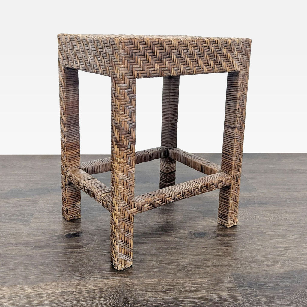 3. Angled view of a rectangular rattan stool featuring a geometric woven design and sturdy, straight legs.