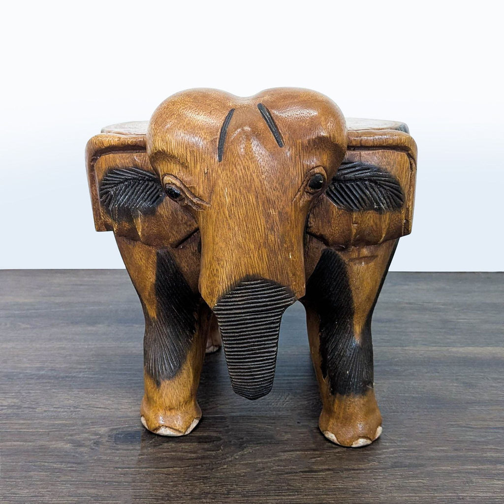 2. Front view of an elephant-shaped wooden ottoman, featuring intricate carvings and textured accents.