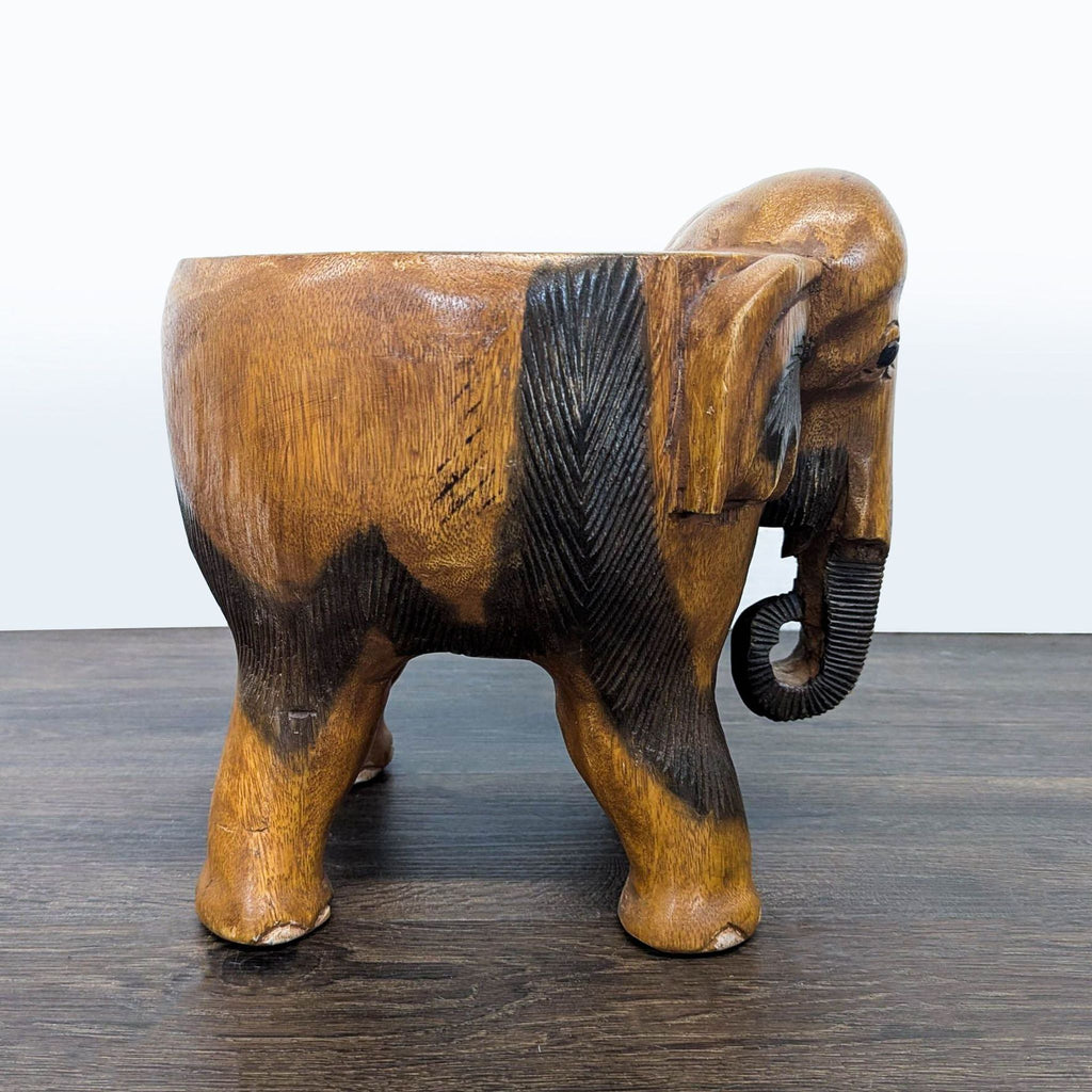 1. Hand-carved wooden elephant stool with detailed trunk and ears, shown in side profile on a dark floor.