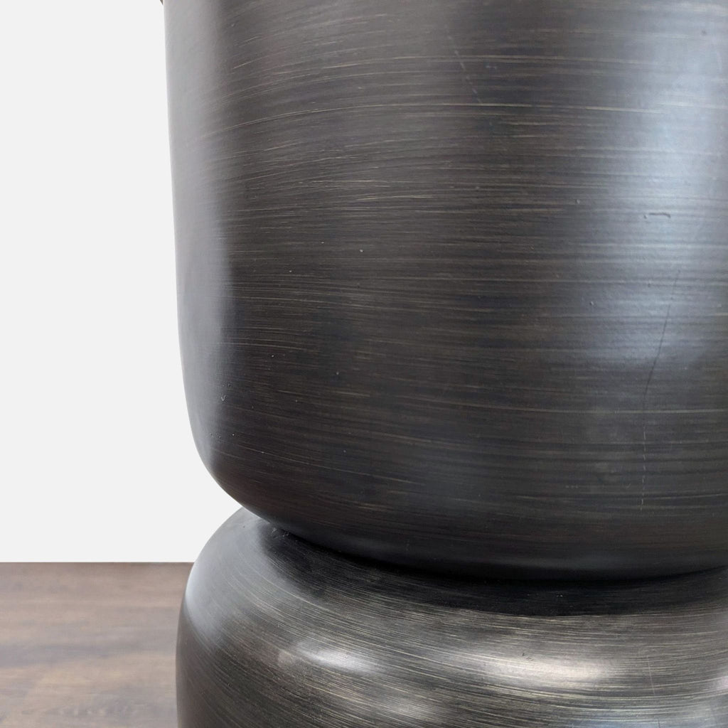 3. Detail view of the brushed black metal base, highlighting the table's smooth, curved design.