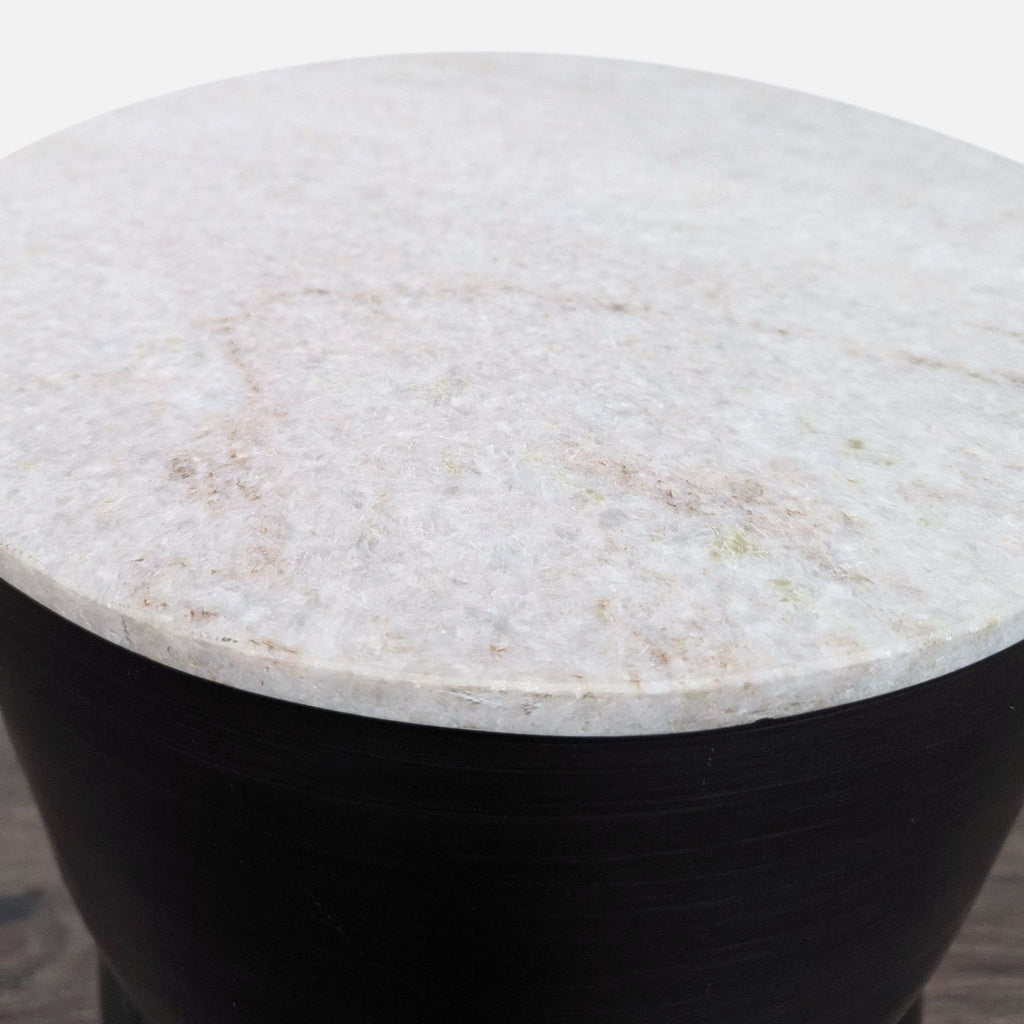 2. Close-up of a round, textured white stone tabletop resting on a dark metal base.