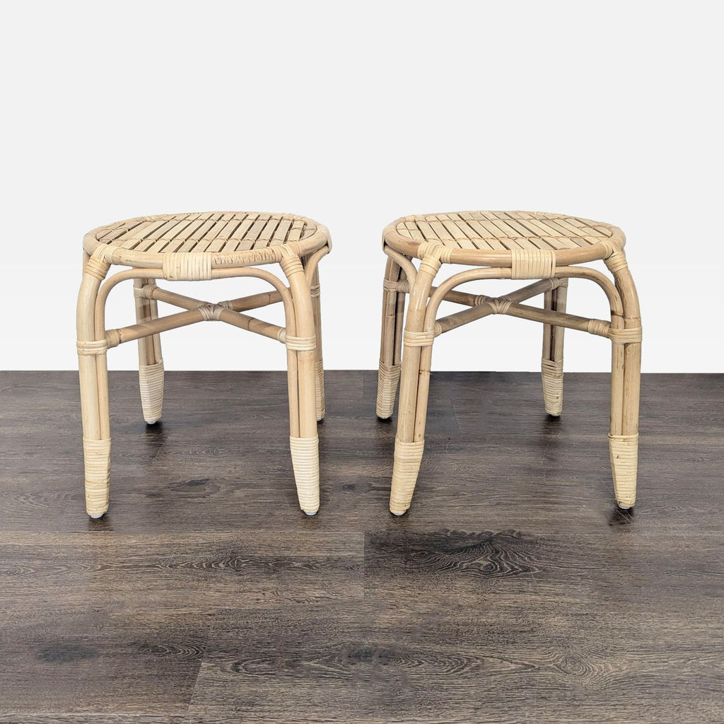 Pair of round rattan stools with woven seats and wrapped detailing, displayed on dark wood flooring.  