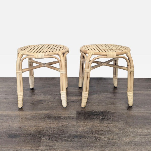 Pair of round rattan stools with woven seats and wrapped detailing, displayed on dark wood flooring.  