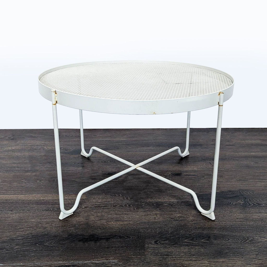 IKEA metal table with white mesh surface, round design and crossbar support, minor rust visible, suitable for indoors/outdoors.
