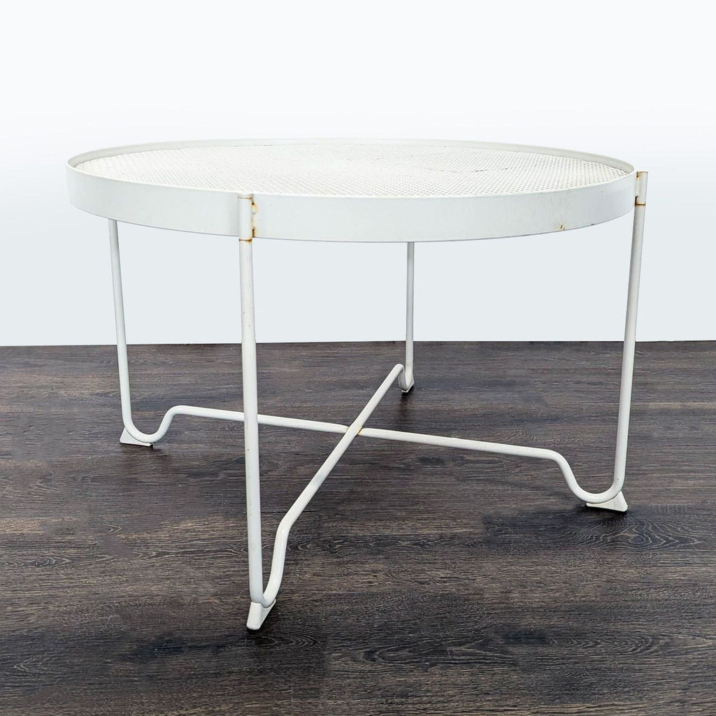 White round IKEA metal table with mesh top and crossbar legs, showing slight rust spots, modern and sturdy.