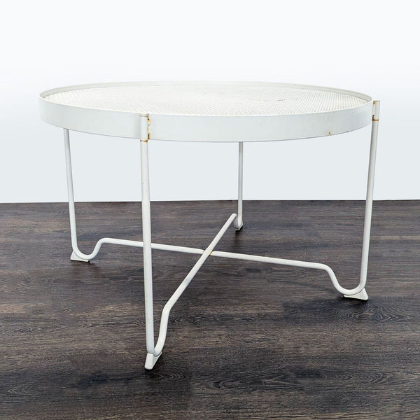 White round IKEA metal table with mesh top and crossbar legs, showing slight rust spots, modern and sturdy.