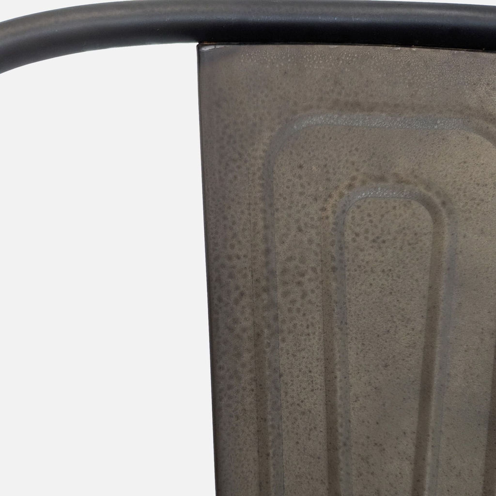 2. Detail of a metal stool backrest with a textured, industrial-style surface and curved top bar.