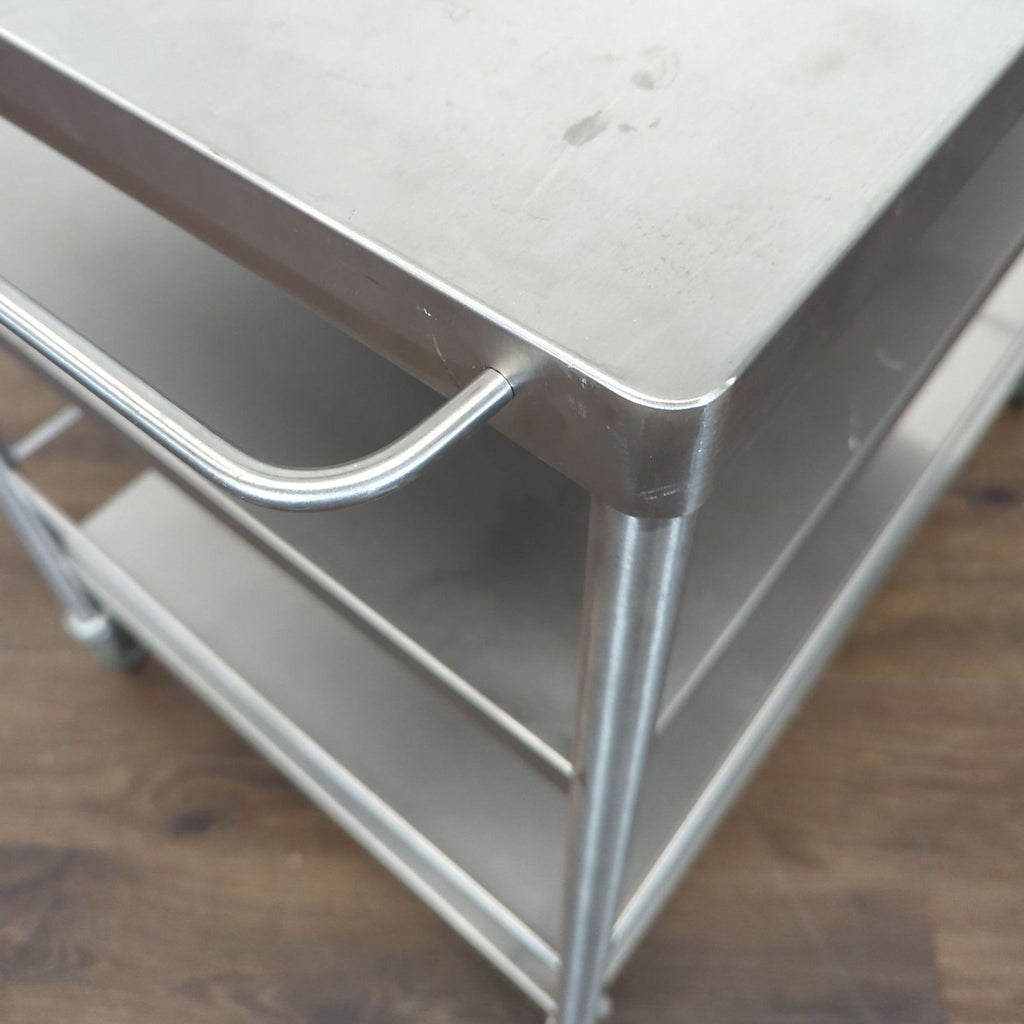 3. Close-up of a sturdy stainless steel cart’s handle and shelf, showing strong construction and finish.
