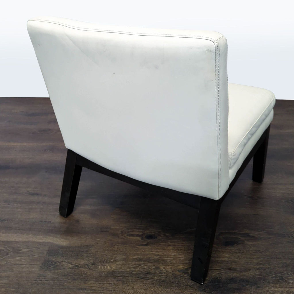 Minimalist lounge chair with a white seat and backrest, supported by black legs, adding style to modern decor.