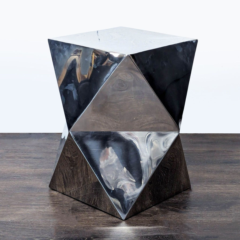 1. Geometric side table with a reflective silver finish and faceted surfaces, placed on a dark wood floor.