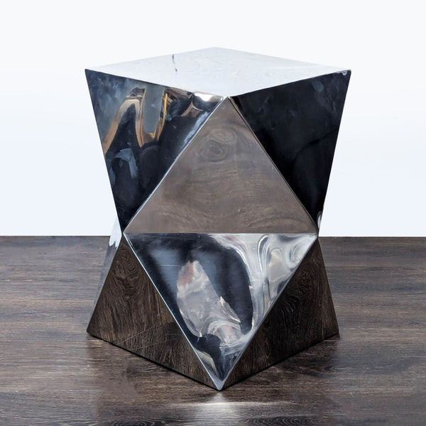 1. Geometric side table with a reflective silver finish and faceted surfaces, placed on a dark wood floor.