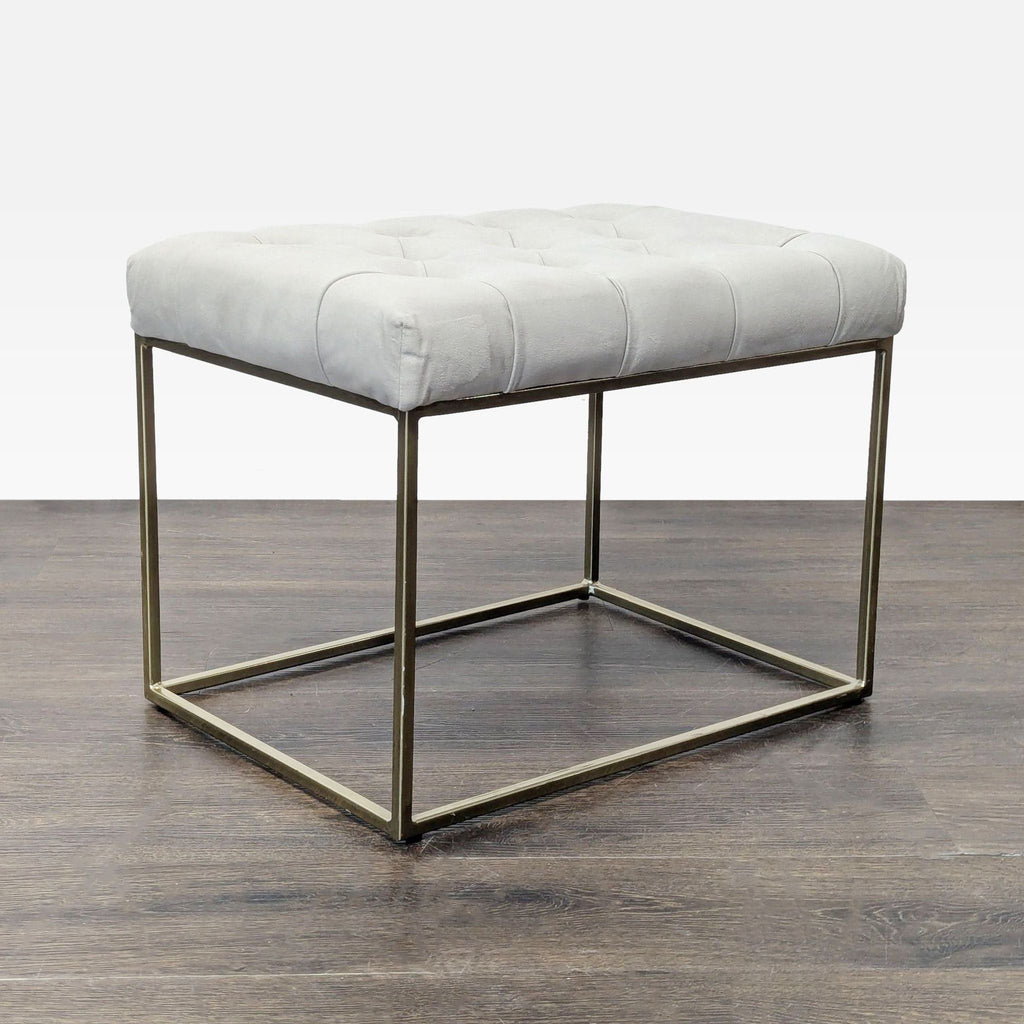 1. Modern Target ottoman with tufted light grey cushion and gold metal base, placed on dark wood floor.  
