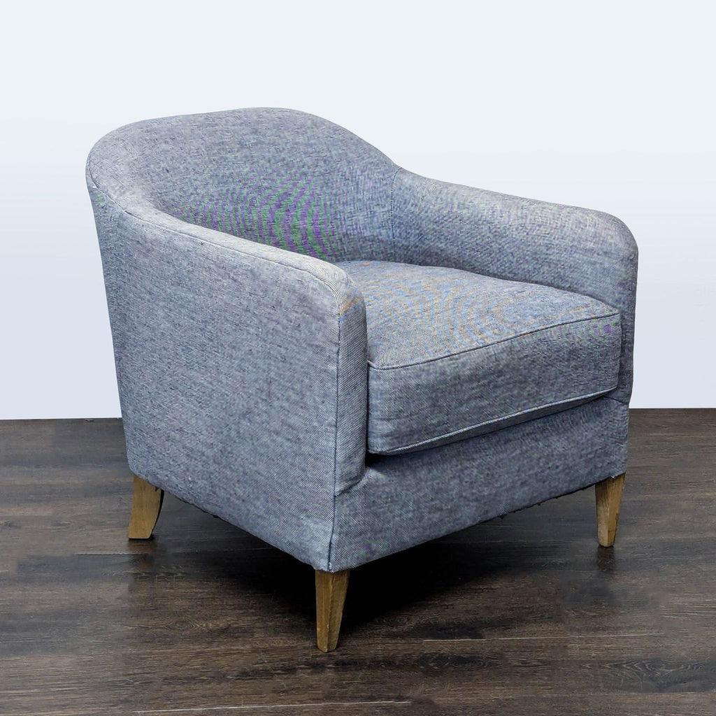 Contemporary blue upholstered lounge chair by Restoration Hardware, featuring a curved back and sturdy wooden legs.