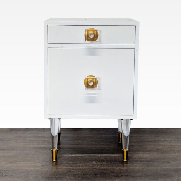 1. White end table with one drawer, one cabinet featuring lucite and brass legs and hardware, shown from the front.