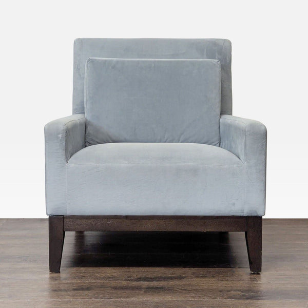 Front view of a West Elm lounge chair in soft gray fabric with dark wood legs and a matching back cushion.