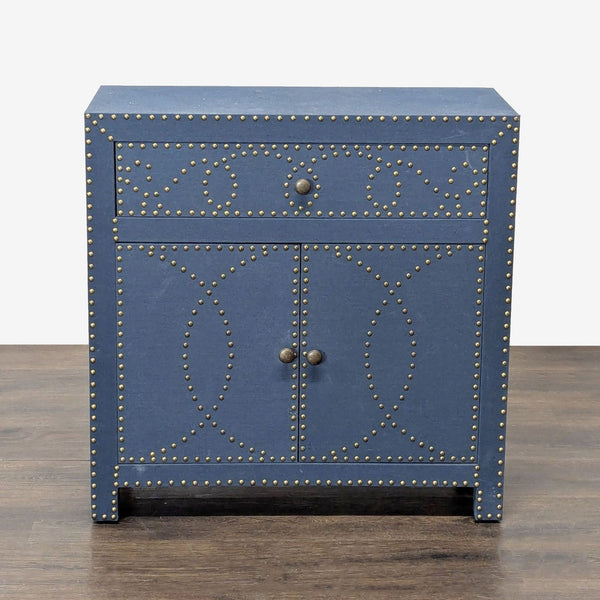 1. Front view of Bungalow Rose navy linen cabinet with double doors, one drawer, and decorative nailhead trim.